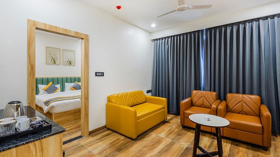 Lemonridge Hotels, KPHB | Hotel room with a seating area, including a yellow sofa and armchairs. Relaxing space.